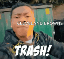 a man is taking a selfie in front of a dumpster with the words cleveland browns trash written on it .