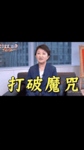 a woman is sitting in front of a sign that says 2022 on it