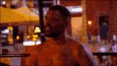 a shirtless man is standing in a boxing ring at night .