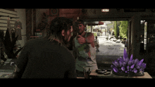 a man in a tank top that says aloha is talking to another man in a store