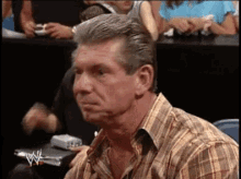 a man in a plaid shirt is sitting at a table with a wwe logo on it .