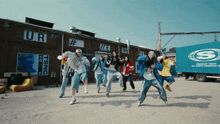 a group of people are dancing in front of a building that says ur and tsnc