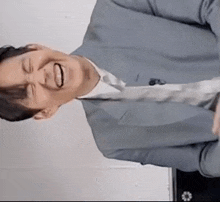 a man in a suit and tie is laughing and making a funny face .