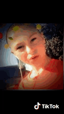 a girl wearing headphones and a flower in her hair is on a tik tok video