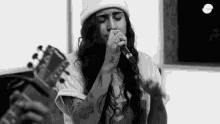 a woman is singing into a microphone while playing a guitar .