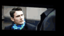 a man in a suit and scarf is looking at another man