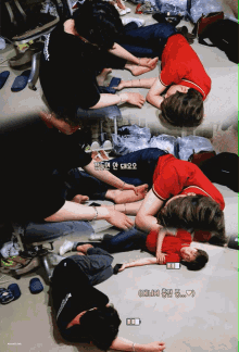 a group of people laying on the floor with one wearing a red shirt that says ' bts ' on the back
