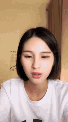 a woman with short black hair is wearing a white t-shirt with the letter t on it