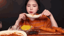 a woman is eating food with chopsticks from a plate