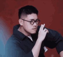 a man wearing glasses and a black shirt is making a gesture with his finger