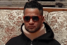 a man wearing a neck brace and sunglasses sitting on a couch .