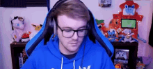 a man wearing glasses and headphones is sitting in a chair in front of a video game console .