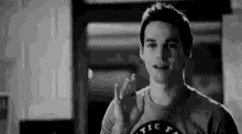 a man in a t-shirt is giving the middle finger in a black and white photo .