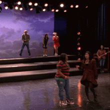 a group of people standing on a stage with a purple backdrop