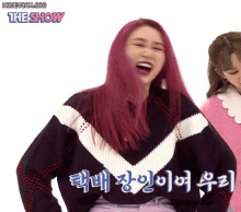 a woman with pink hair is laughing in front of a sign that says the show on it