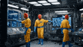 three men in yellow jumpsuits are standing in a room with a screen that says doomsday room