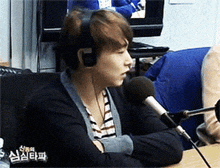 a man wearing headphones sits in front of a microphone with chinese writing on the bottom