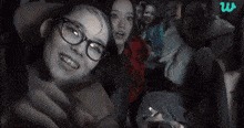 a group of people are sitting in a car and one of the girls is pointing at the camera .