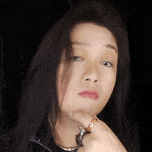 a woman wearing a ring on her finger looks at the camera