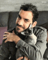 a man with a beard is holding a hairless cat in his lap