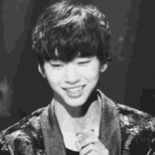 a young man is smiling while holding a microphone in his hand .