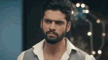a man with a beard is looking at the camera .