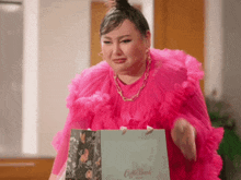 a woman in a pink dress is holding a gift bag that says coffee bean