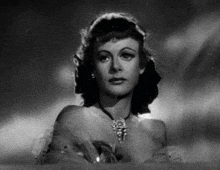 a black and white photo of a woman wearing a necklace in a bathtub .