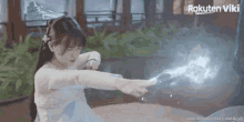 a girl in a white dress is holding a sword in her hand and pointing at it .