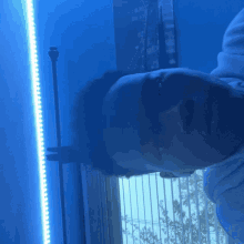 a man is laying down in front of a window with a blue light behind him