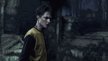 a young man in a yellow shirt is standing in a dark room .