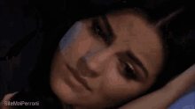 a close up of a woman laying on a bed with her hand on her head .