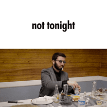 a man sitting at a table with a cigarette and the words not tonight