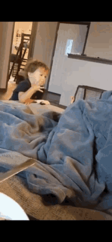 a little boy is sitting on a couch with a blanket and a knife .