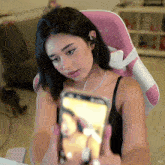 a woman sitting in a pink chair looking at a cell phone