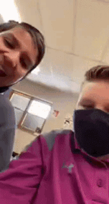 two people wearing face masks are posing for a picture in a classroom