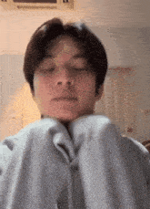 a young man with his eyes closed is wearing a grey sweatshirt