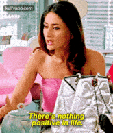 a woman in a pink top is sitting at a table with handbags and says `` there 's nothing positive in life '' .