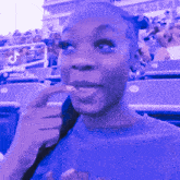 a woman in a blue shirt is sitting in a stadium with a sign that says tik tok