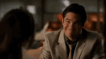 a man in a suit and tie looks at a woman