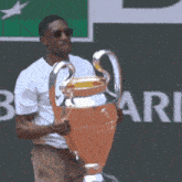 a man in a white shirt holds a trophy in front of a sign that says rie