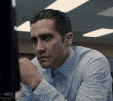 a man in a blue shirt is looking at a screen