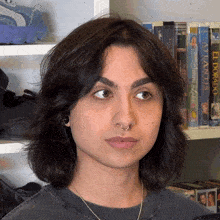 a woman stands in front of a shelf full of books one of which is titled el dorado