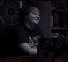 a man wearing a headband is sitting in front of a laptop computer