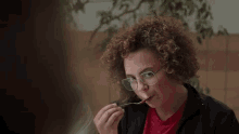 a woman with curly hair is brushing her teeth with a toothbrush and a fork .