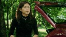 a woman stands in front of a red car with the hood open and the word fun on the bottom right