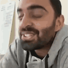 a man with a beard is smiling with his eyes closed