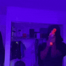 a woman is standing in a room with purple lights .