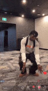 a man in a white sweatshirt is dancing in a room with a sign that says ' exit ' on it