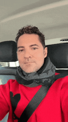 a man wearing a red scarf and a red sweater is sitting in a car